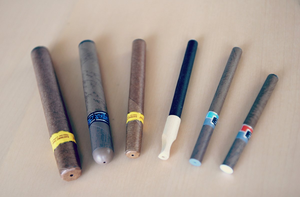 Assorted vape devices arranged beside an e-liquid bottle
