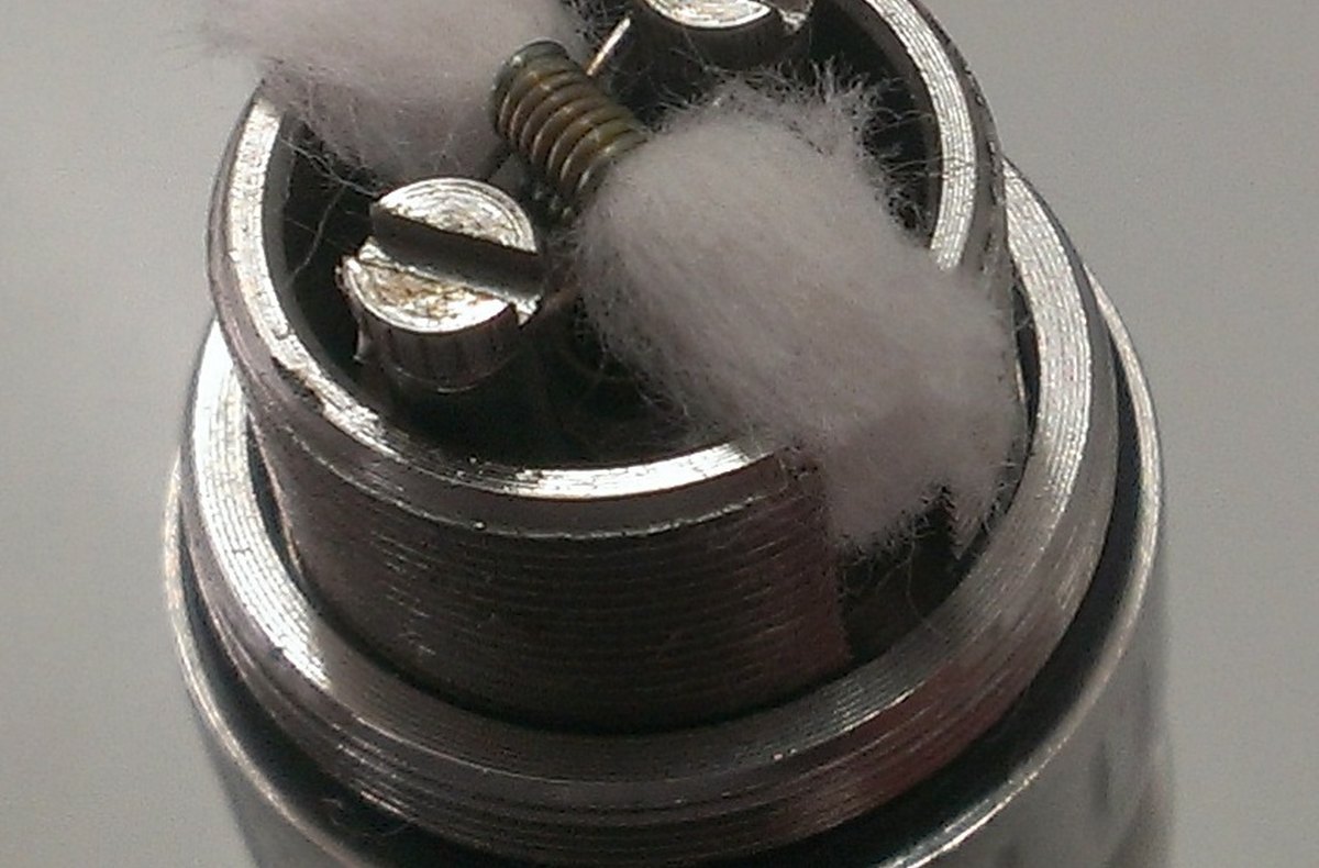 Exposed vape coil and cotton wick inside an atomizer